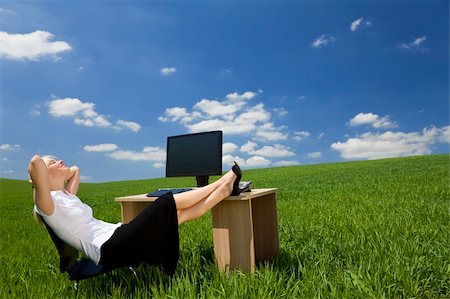 relaxed attractive woman feet up - Business concept shot of a beautiful young woman relaxing at a desk in a green field with a bright blue sky. Shot on location. Photographie de stock - Aubaine LD & Abonnement, Code: 400-04610280