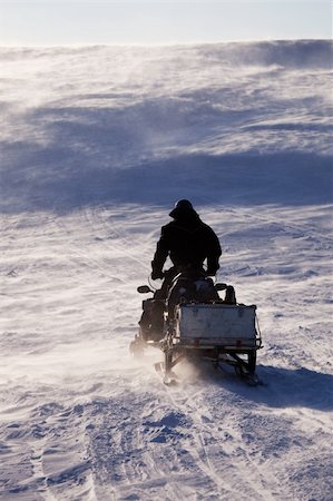 simsearch:400-05140080,k - A man sitting on a snowmobile on a barren snow landscape Fotografie stock - Microstock e Abbonamento, Codice: 400-04610535