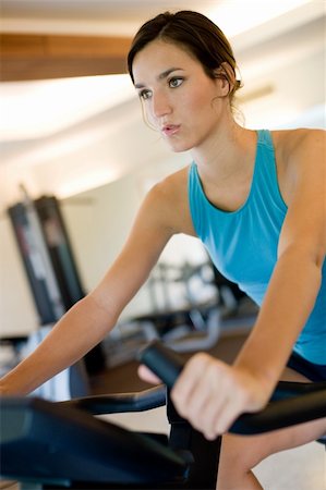 eastwestimaging (artist) - A young woman using a cycling machine in the gym Foto de stock - Super Valor sin royalties y Suscripción, Código: 400-04610654