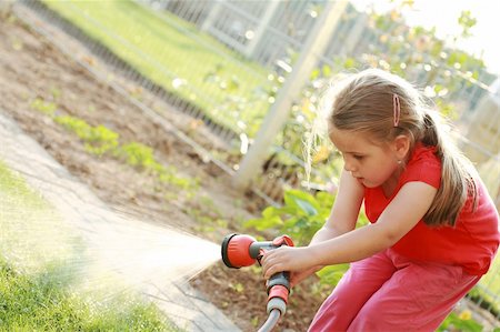 spraying water hose - Little girl watering the grass in the garden Stock Photo - Budget Royalty-Free & Subscription, Code: 400-04624173