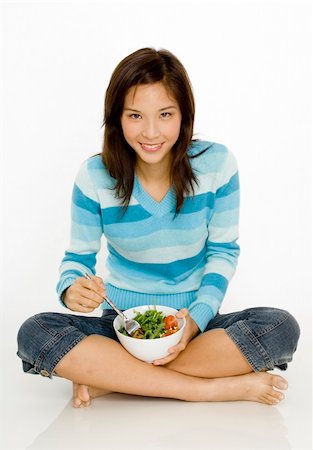 A young asian woman sitting cross-legged with a bowl of salad Stock Photo - Budget Royalty-Free & Subscription, Code: 400-04625800