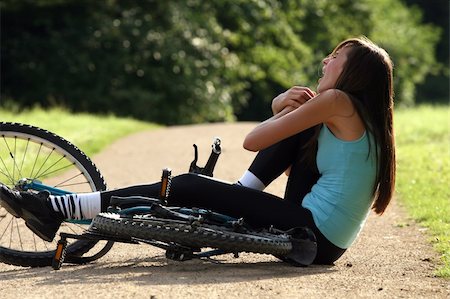 Female bike rider takes a tumble and holding her knee from pain Stock Photo - Budget Royalty-Free & Subscription, Code: 400-04622319