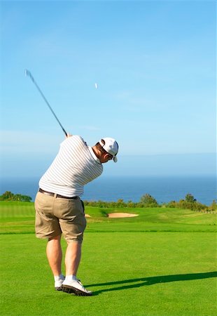 simsearch:400-04622368,k - Young male golfer hitting the ball from the fairway next to the ocean on a beautiful summer day Foto de stock - Super Valor sin royalties y Suscripción, Código: 400-04622370