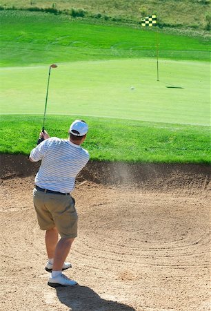 simsearch:400-04622368,k - Young male golfer hitting the ball from the sand bunker on a beautiful summer day Foto de stock - Super Valor sin royalties y Suscripción, Código: 400-04622371