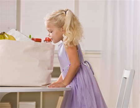 shopping bags in kitchen - A young girl is peeking into the sack of groceries on the kitchen table.  She is looking away from the camera.  Horizontally framed shot. Stock Photo - Budget Royalty-Free & Subscription, Code: 400-04622674