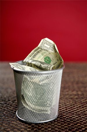 simsearch:695-05776758,k - Dollar bank notes on the trash over brown tablecloth, red background Stock Photo - Budget Royalty-Free & Subscription, Code: 400-04623534