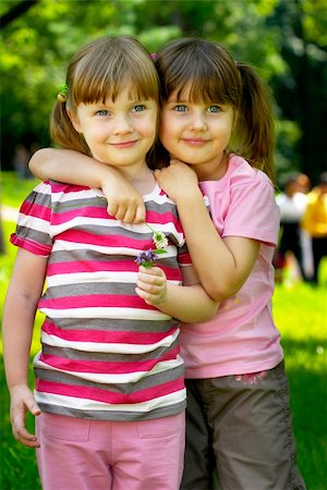 simsearch:400-05352235,k - Two little girlfriends standing together in the park, one hugs another. Photographie de stock - Aubaine LD & Abonnement, Code: 400-04623721