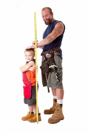 parent child measure - Father wearing tool belt with toy hammer and measuring tape, measures height of cute son dressed in orange apron, isolated. Stock Photo - Budget Royalty-Free & Subscription, Code: 400-04634542