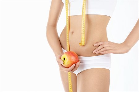 Close up in front of a beautiful female body, a measuring tape and an apple in hands Stock Photo - Budget Royalty-Free & Subscription, Code: 400-04637285