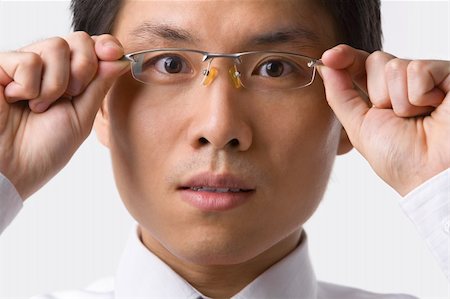 simsearch:400-04639378,k - A young Asian businessman gazing at camera while holding glasses to camera Stock Photo - Budget Royalty-Free & Subscription, Code: 400-04639378
