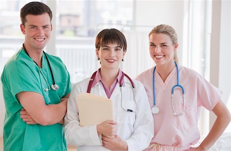 Three doctors are smiling at the camera in a doctors' office.  Horizontally framed shot. Stock Photo - Budget Royalty-Free & Subscription, Code: 400-04631099