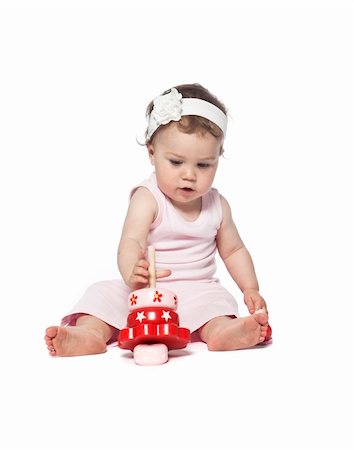 family values - Baby in pink clothes playing with a red toy isolated on white Photographie de stock - Aubaine LD & Abonnement, Code: 400-04645808