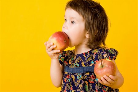 Little girl with two apple isolated on yellow  background Fotografie stock - Microstock e Abbonamento, Codice: 400-04646102