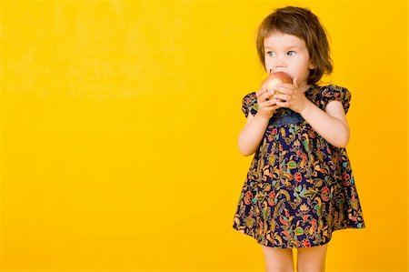 Little girl with apple isolated on yellow  background Fotografie stock - Microstock e Abbonamento, Codice: 400-04646103