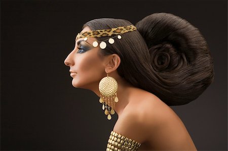 Portrait of the young woman in a profile in east style with a beautiful hairdress and gold ornaments on a black background. Stock Photo - Budget Royalty-Free & Subscription, Code: 400-04646659