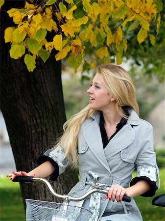 Young beautiful blond woman on bicycle under maple tree. Fall Fotografie stock - Microstock e Abbonamento, Codice: 400-04646783