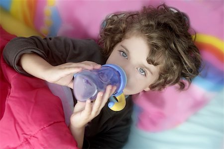 Adorable little brunette girl drinking bottle over pink pillow Stock Photo - Budget Royalty-Free & Subscription, Code: 400-04649255