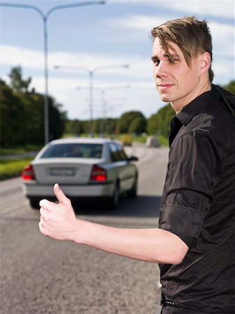 A young man hitchiking on the road Stock Photo - Budget Royalty-Free & Subscription, Code: 400-04640474