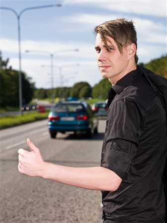 A young man hitchiking on the road Stock Photo - Budget Royalty-Free & Subscription, Code: 400-04640475