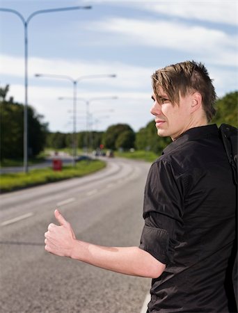 A young man hitchiking on the road Stock Photo - Budget Royalty-Free & Subscription, Code: 400-04640476