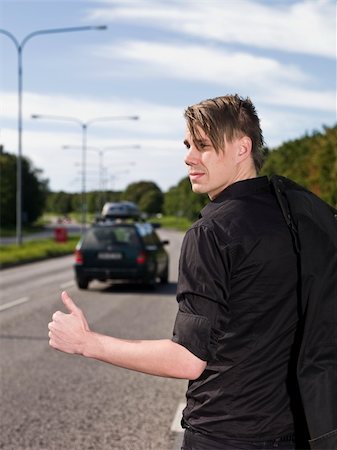 A young man hitchiking on the road Stock Photo - Budget Royalty-Free & Subscription, Code: 400-04640477