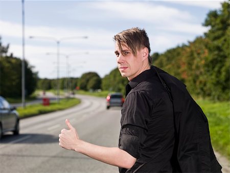 A young man hitchiking on the road Stock Photo - Budget Royalty-Free & Subscription, Code: 400-04640473