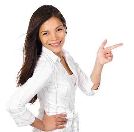 Smiling and confident woman in white pointing at your product while looking at the camera. Isolated on white background.Beautiful mixed asian / caucasian model. Stock Photo - Budget Royalty-Free & Subscription, Code: 400-04642685