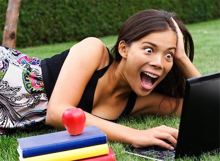 Student with laptop surprised while chatting / checking email / reading gossip news in the park. Beautiful mixed race caucasian / asian model. Stock Photo - Budget Royalty-Free & Subscription, Code: 400-04642692