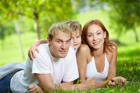 simsearch:400-04654326,k - Young family consisting of three persons lies on a summer lawn Stock Photo - Budget Royalty-Free & Subscription, Code: 400-04654319