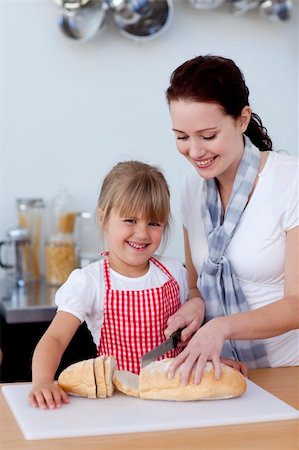 Mother teaching daughter how to cut bread in kitchen Stock Photo - Budget Royalty-Free & Subscription, Code: 400-04654567