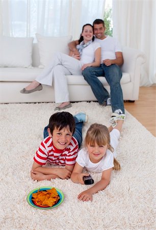 food salt kids - Happy children watching television on floor in living-room with their parents on sofa Photographie de stock - Aubaine LD & Abonnement, Code: 400-04654590