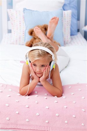 simsearch:400-05717354,k - Little girl lying in bed with a headphones on listening to the music Stock Photo - Budget Royalty-Free & Subscription, Code: 400-04654718