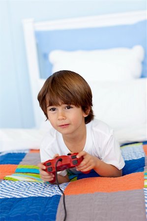 simsearch:400-04199147,k - Young boy playing videogames sitting in his bed Photographie de stock - Aubaine LD & Abonnement, Code: 400-04654720