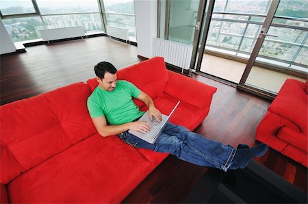 simsearch:400-05013654,k - young man relax on red sofa and work on laptop at home indoor Photographie de stock - Aubaine LD & Abonnement, Code: 400-04655145