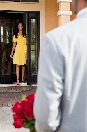 simsearch:400-04655735,k - A romantic African American man bringing flowers to his happy wife or girlfriend who is standing waiting for him at the door of their home. Stockbilder - Microstock & Abonnement, Bildnummer: 400-04655735
