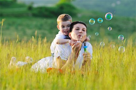 happy child and woman outdoor playing with soap bubble on meadow Stock Photo - Budget Royalty-Free & Subscription, Code: 400-04659497