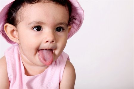 Beautiful baby with tongue hanging out. Dressed in pink Foto de stock - Royalty-Free Super Valor e Assinatura, Número: 400-04651986