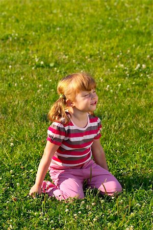 Little girl sitting on the grass in the park, dreaming of something Fotografie stock - Microstock e Abbonamento, Codice: 400-04652709