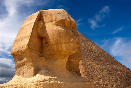 simsearch:400-05892147,k - Diagonal front-on view of Sphinx with a pyramid in the background. Blue skies and clouds overhead Foto de stock - Super Valor sin royalties y Suscripción, Código: 400-04652920