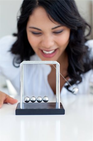 simsearch:400-05282436,k - Businesswoman having fun with Newton balls in office Fotografie stock - Microstock e Abbonamento, Codice: 400-04653079