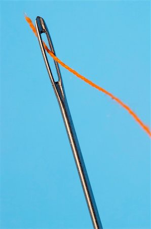 Orange thread in the needle's eye isolated over blue background Fotografie stock - Microstock e Abbonamento, Codice: 400-04653468