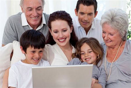 simsearch:400-04575374,k - Smiling family sitting on sofa using a laptop Stock Photo - Budget Royalty-Free & Subscription, Code: 400-04653630