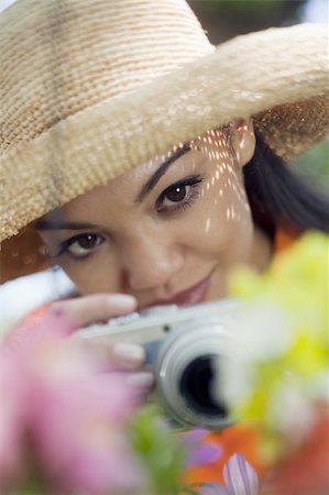 Close-up of a young woman in a sun hat, taking pictures of flowers. Vertical format. Stock Photo - Budget Royalty-Free & Subscription, Code: 400-04653837