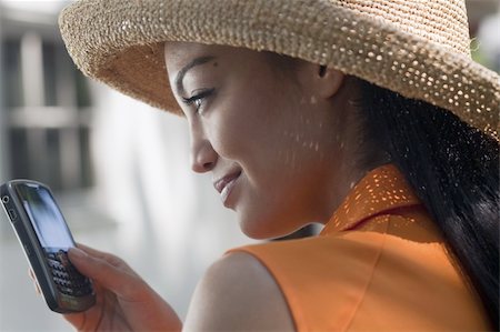 edbockstock (artist) - Close-up side view of a young woman wearing a sun hat and texting on her cell phone. Horizontal format. Photographie de stock - Aubaine LD & Abonnement, Code: 400-04653840