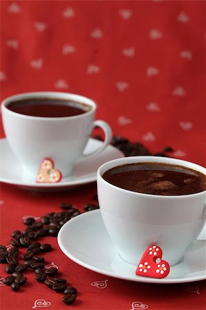 simsearch:400-06526962,k - Cups of coffee with little ceramic hearts and coffee-beans on a red background. Shallow dof, copy space Foto de stock - Royalty-Free Super Valor e Assinatura, Número: 400-04665018