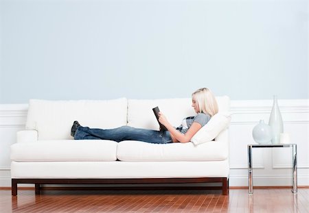 Full length view of woman reclining on white couch and reading a book. Horizontal format. Fotografie stock - Microstock e Abbonamento, Codice: 400-04666300