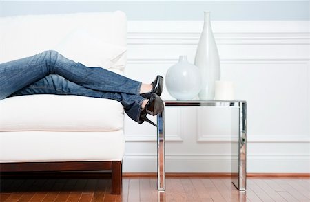 Cropped view of woman reclining on white couch next to an end table holding vases, with only her legs visible. Horizontal format. Stock Photo - Budget Royalty-Free & Subscription, Code: 400-04666382