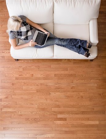 Full length overhead view of woman reclining on white couch and using a laptop. Vertical format. Stock Photo - Budget Royalty-Free & Subscription, Code: 400-04666428