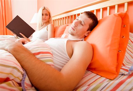 simsearch:614-06718748,k - Woman holds book and watches man sleeping next to her. Horizontal format. Stock Photo - Budget Royalty-Free & Subscription, Code: 400-04666435