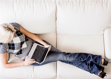 Overhead view of woman reclining on white couch and using a laptop. Horizontal format. Fotografie stock - Microstock e Abbonamento, Codice: 400-04666430